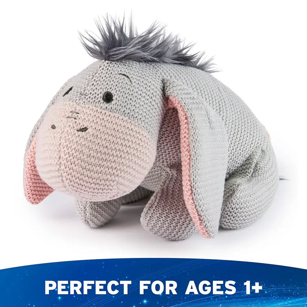 Disney Eeyore plush appears from a right angled view, showing its soft knit construction, floppy limbs, pink inner ears, and gentle slouched posture that adds to its classic, comforting character style.