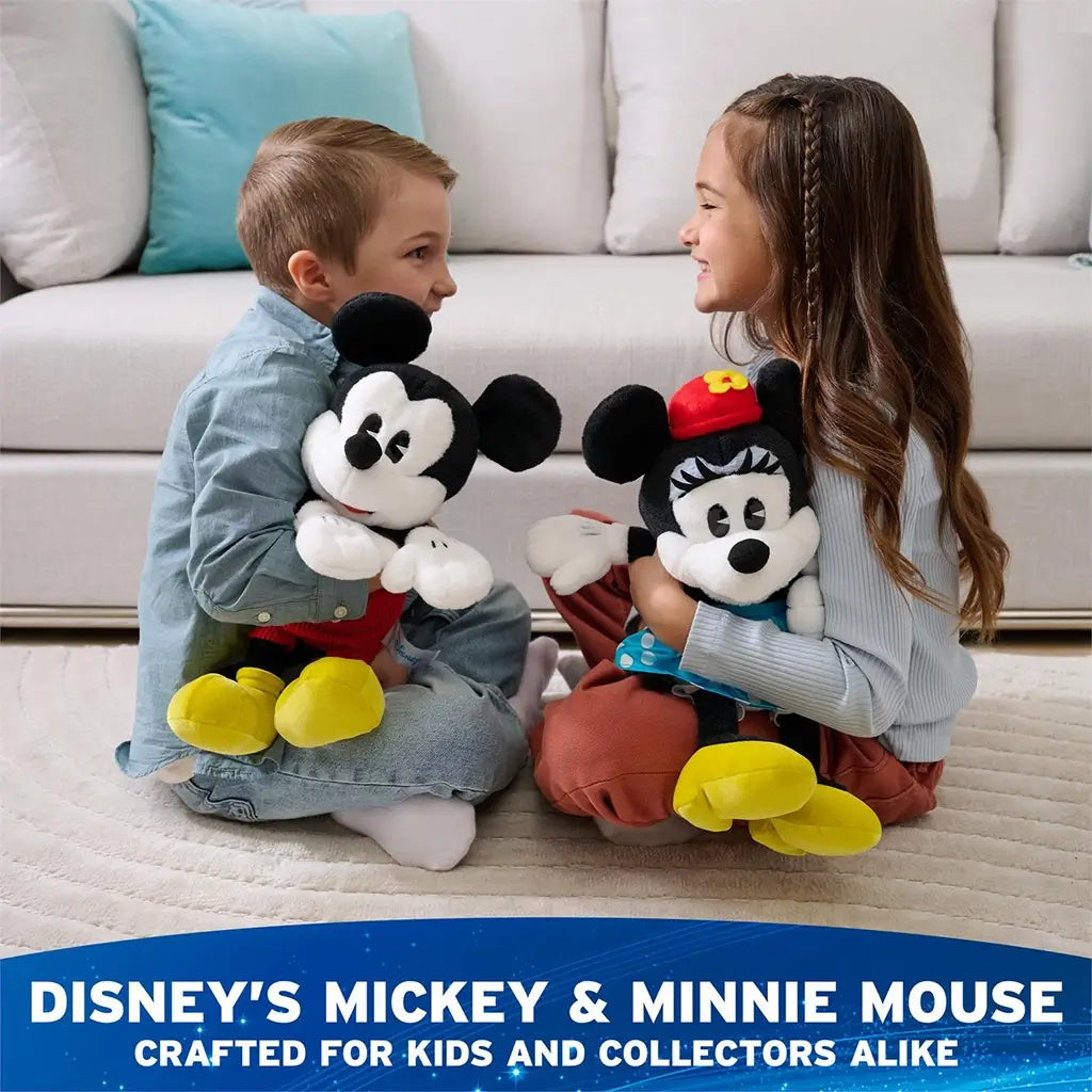 Disney Minnie Mouse plush toy in black and white soft fabric with classic seated character form, red hat with yellow flower, blue polka dot skirt, white gloves, and yellow shoes, displayed with another Minnie and Mickey plush as collectible décor.