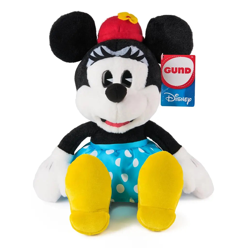 Disney Minnie Mouse plush in black and white fuzzy fabric with soft velour texture, classic seated character shape, red hat with yellow flower, blue polka dot skirt, white gloves, and yellow shoes, photographed on a clean white studio background.