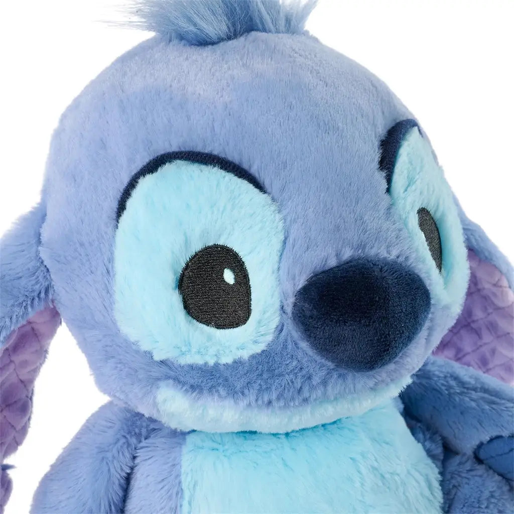 Disney Stitch plush close-up showing light blue and periwinkle plush fabric, smooth stitched facial details, rounded nose, and fuzzy tuft, highlighting soft texture and character design on a white background.