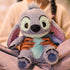 Disney Stitch plush toy crafted from ultra-soft blue fabric with floppy ears and padded feet, intended for cuddling, resting in a child’s hands while seated comfortably on a bed indoors.