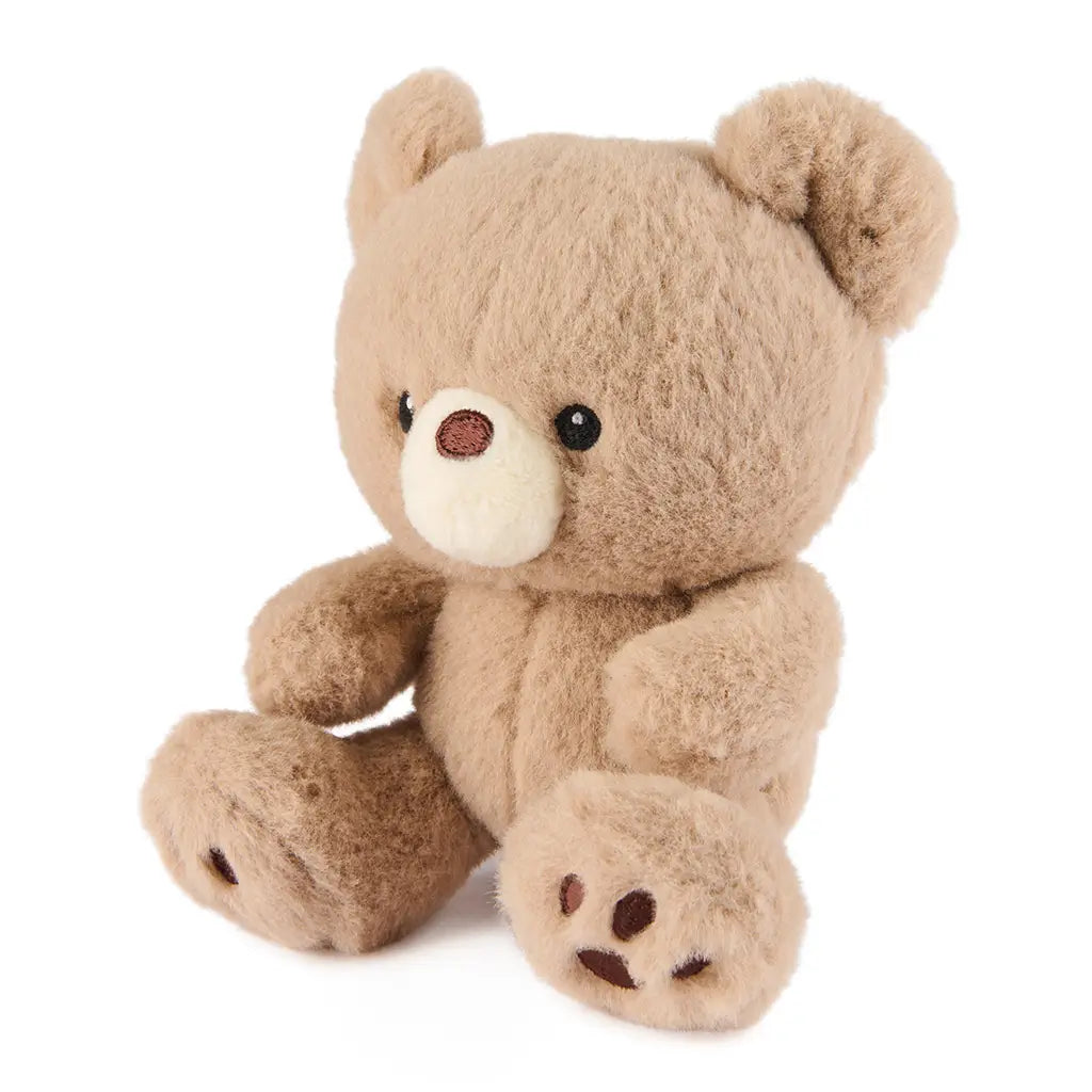 GUND Kai plush teddy bear in light beige textured fabric with rounded limbs and soft shape, angled view highlighting paw pads and stitching, small stuffed toy on a plain white background