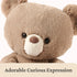 GUND teddy bear close-up showing warm beige plush fur, velvety texture, rounded head shape, shiny black safety eyes, and a soft cream muzzle that creates an adorable, curious expression against a clean white background.