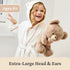 GUND teddy bear lifestyle image showing beige plush fur, oversized rounded head and ears, and a soft squishy body, held by a smiling child in a bright indoor setting to illustrate scale, comfort, and suitability for all ages.