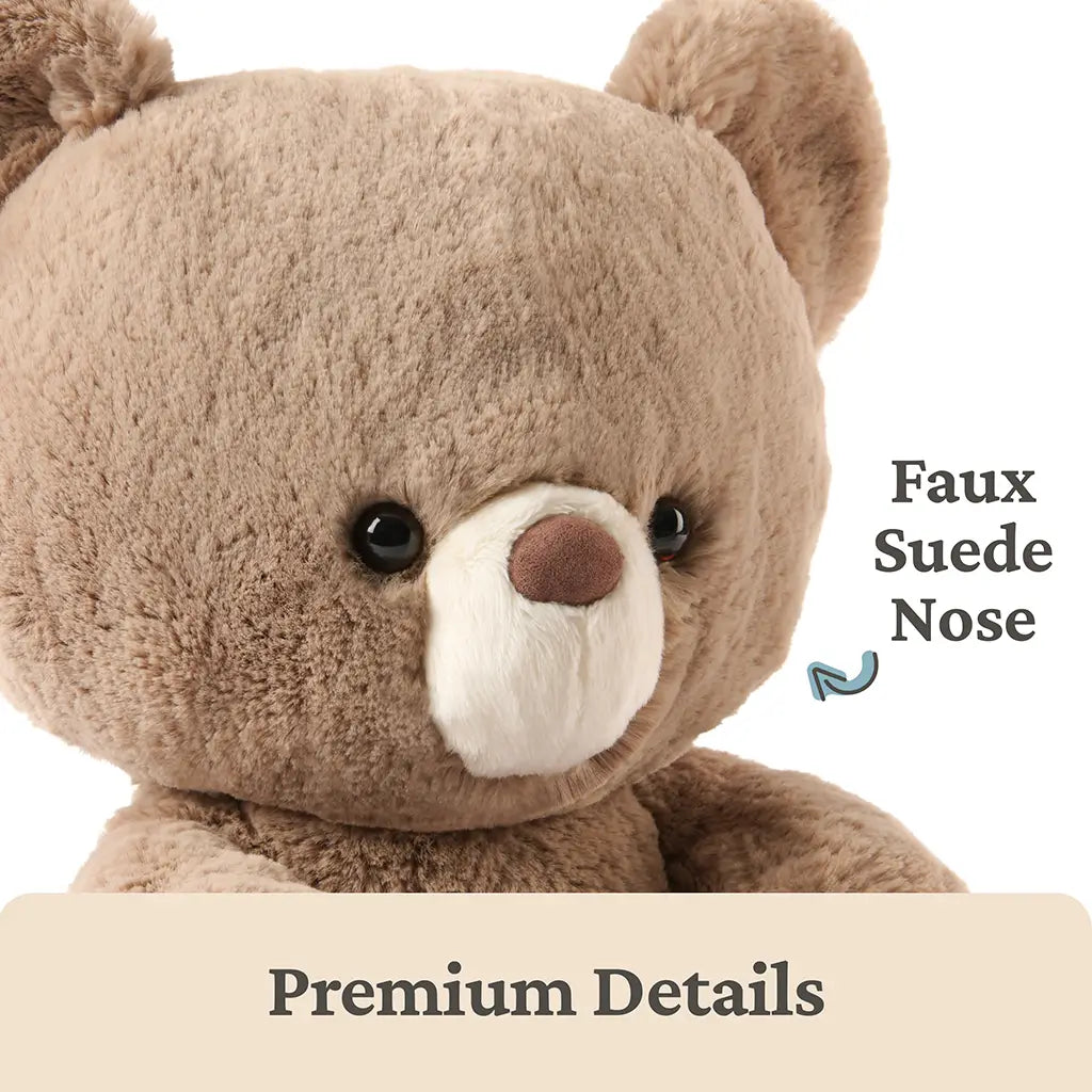 GUND teddy bear premium detail image highlighting warm beige plush fur, ultra-soft texture, rounded face shape, glossy black eyes, and a contrasting faux suede brown nose that emphasizes thoughtful craftsmanship and quality materials.