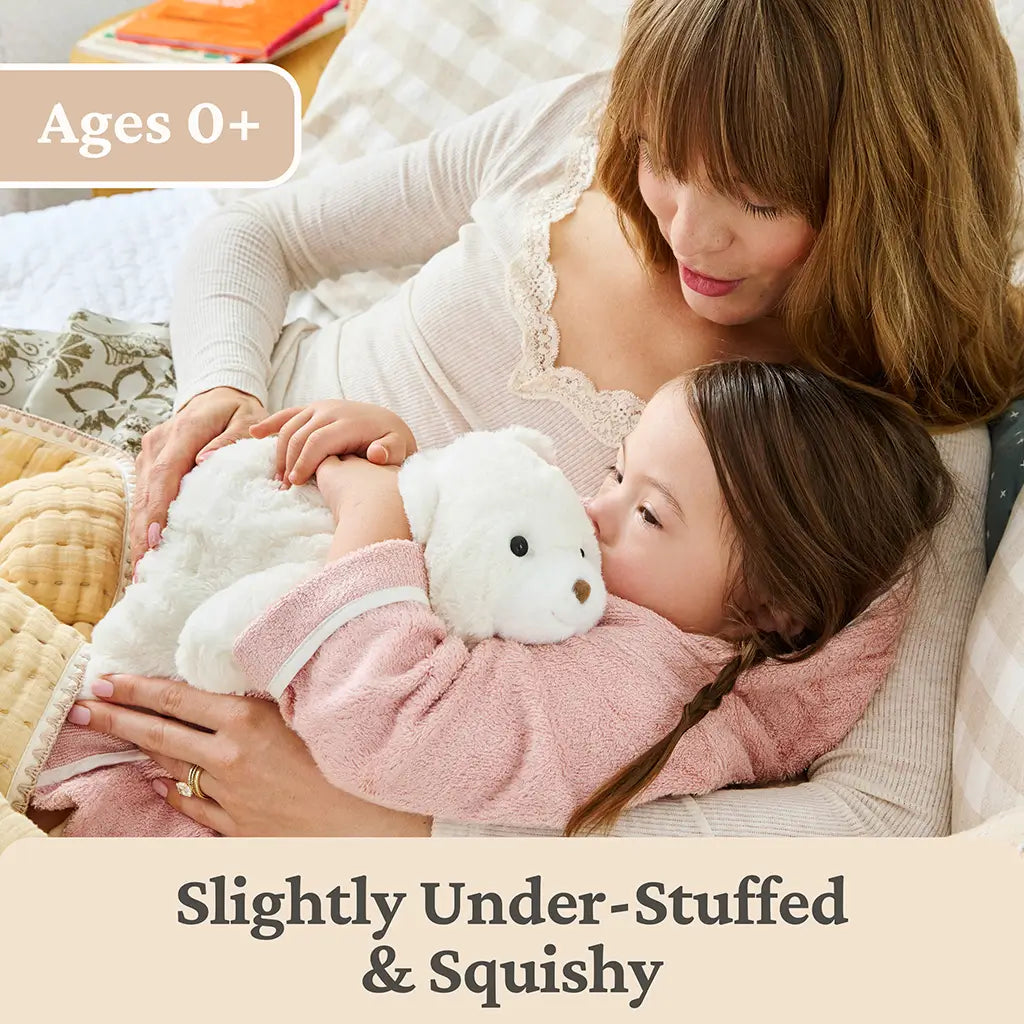 GUND Snuffles teddy bear plush in white velour fabric with a relaxed rounded body, shown cuddled by a child and adult, highlighting slightly under-stuffed squishy comfort suitable for all ages.