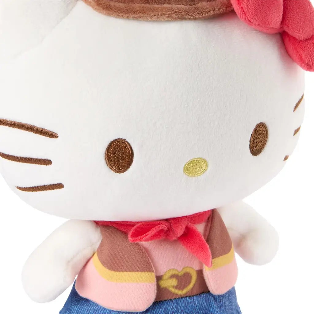 Hello Kitty cowgirl plush close-up showing white velour fabric, smooth rounded face shape, embroidered brown eyes and whiskers, yellow nose stitching, red neckerchief, and detailed western outfit textures against a white background.