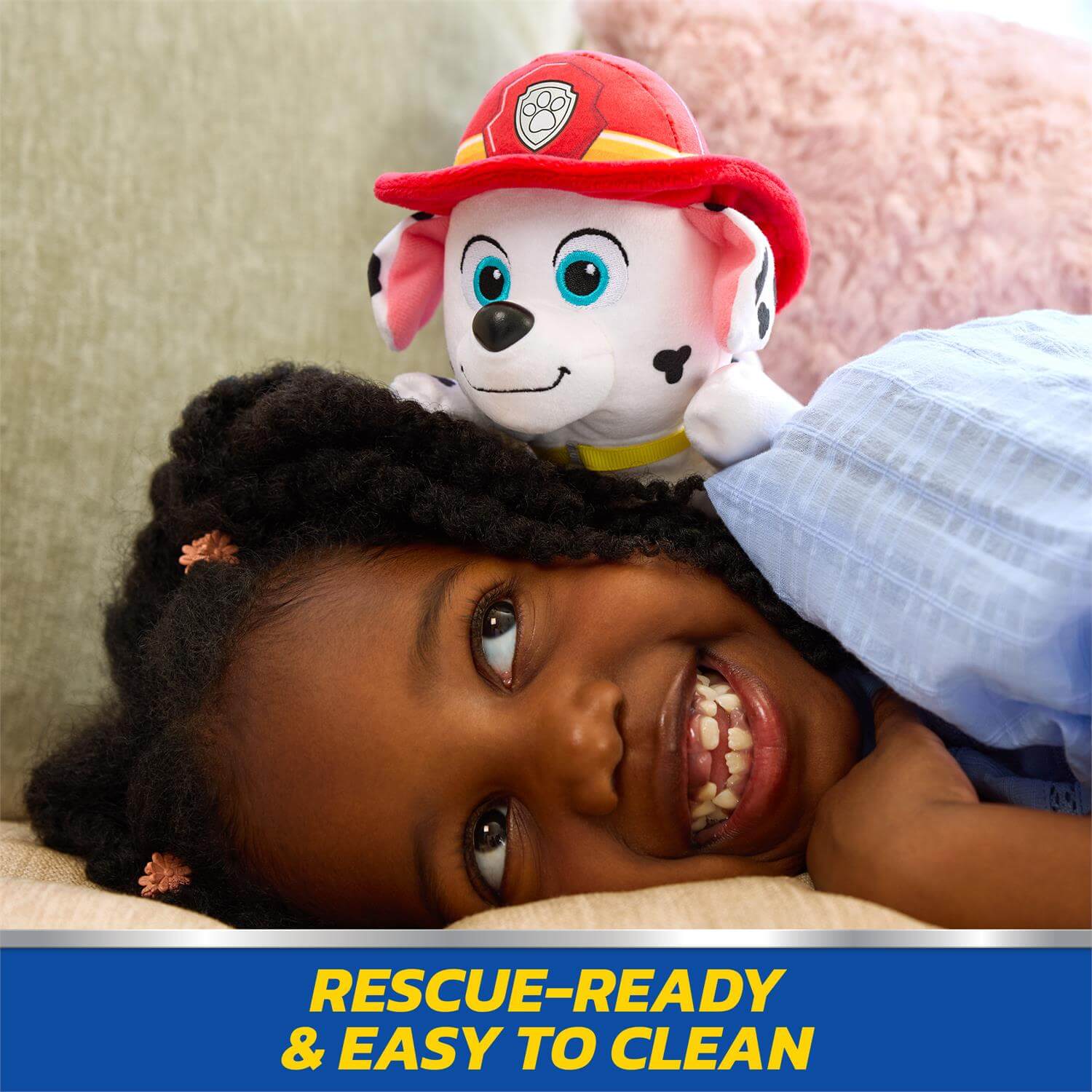 Gund Marshall Lounging 8-Inch Plush .Child with a plush toy wearing a fire helmet, lying on a bed with a 'Rescue-Ready & Easy to Clean' label.