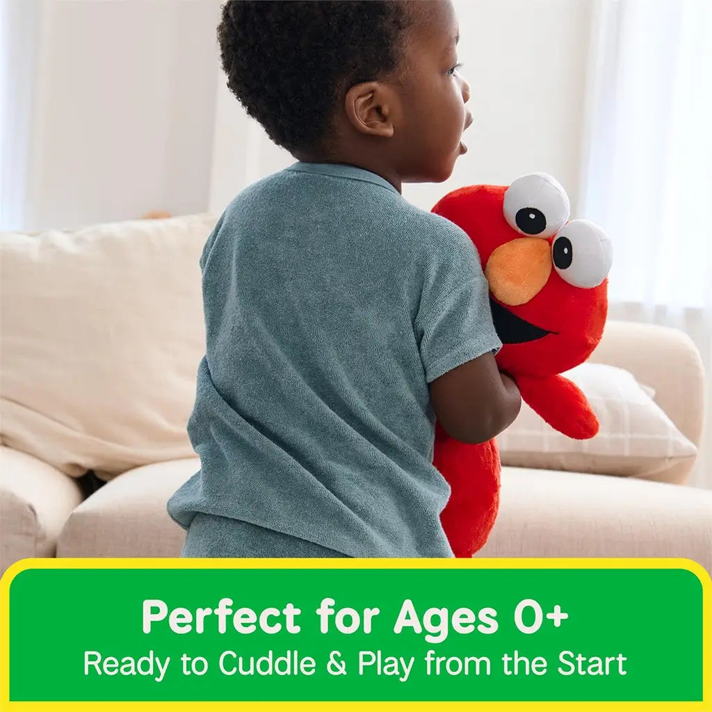GUND Sesame Street Elmo plush toy in bright red plush fabric with floppy arms and embroidered smile, designed for hugging, carried by a young child in a casual living room setting during imaginative play.
