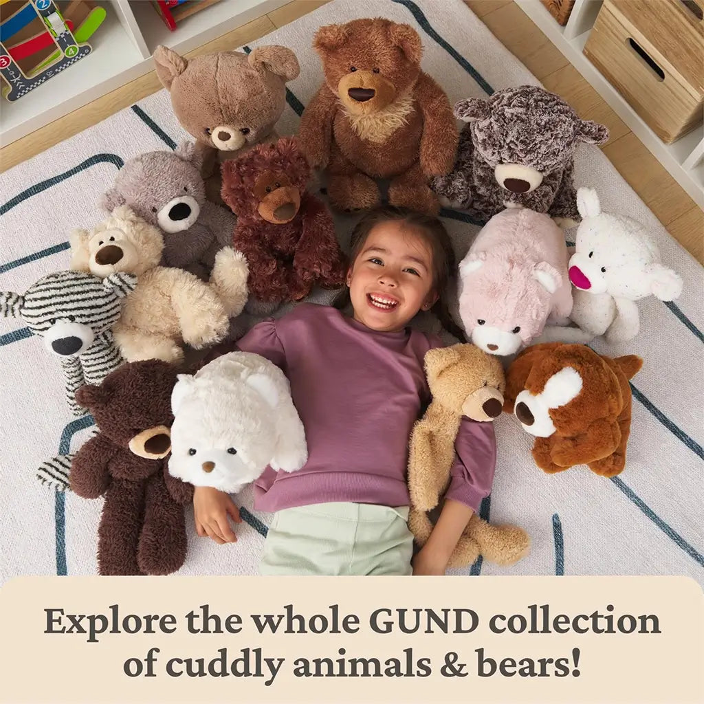 GUND teddy bear plush collection shown in warm neutral brown tones with soft textured fabrics, rounded bear shapes, embroidered noses and paw pads, arranged around a smiling child on a playroom rug to highlight cuddly variety.