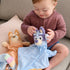 Bluey lovey plush is shown with a baby seated on a sofa, featuring soft pastel blue fabric, floppy blanket body, and friendly embroidered face, supporting gentle play and on-the-go soothing from birth.