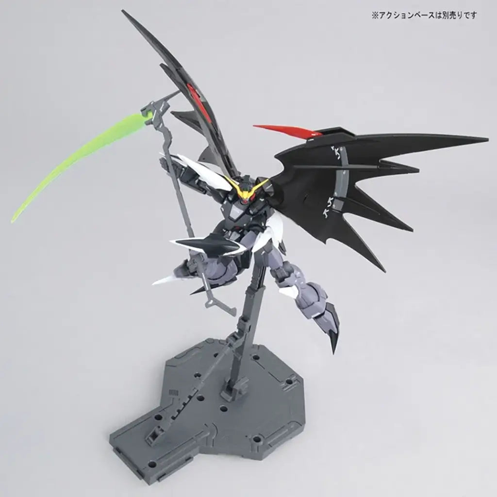 Bandai Gundam Deathscythe Hell figure in black and gray plastic with red wing tips, sharp batlike wings spread wide, holding a glowing green beam scythe, posed dynamically on a stand over a neutral white backdrop.
