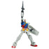 Gundam RX-78-2 poseable model in white, blue, red, and yellow plastic with articulated joints, raising a gray rifle overhead and holding a shield, displayed against a plain white backdrop.