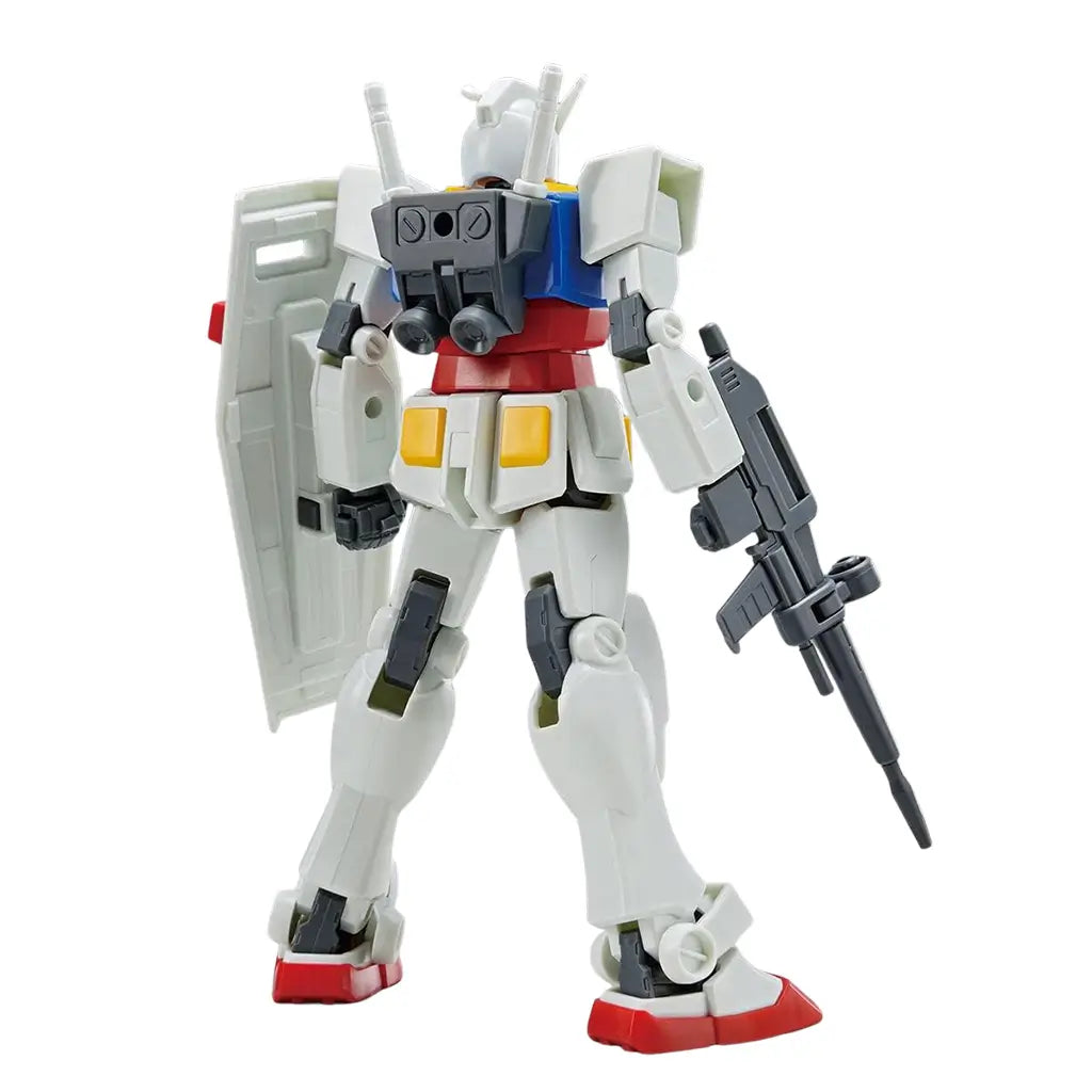 Gundam RX-78-2 model kit in white plastic with blue torso and red accents, shown from rear with backpack thrusters, shield, and rifle, standing upright against a clean white studio background.