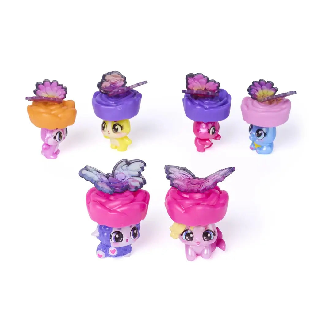 Hatchimals Bloomables characters angled view showing pastel pink, yellow, blue, and purple mini figures with glossy plastic bodies, large eyes, butterfly wings, and flower-shaped bases arranged on white background.