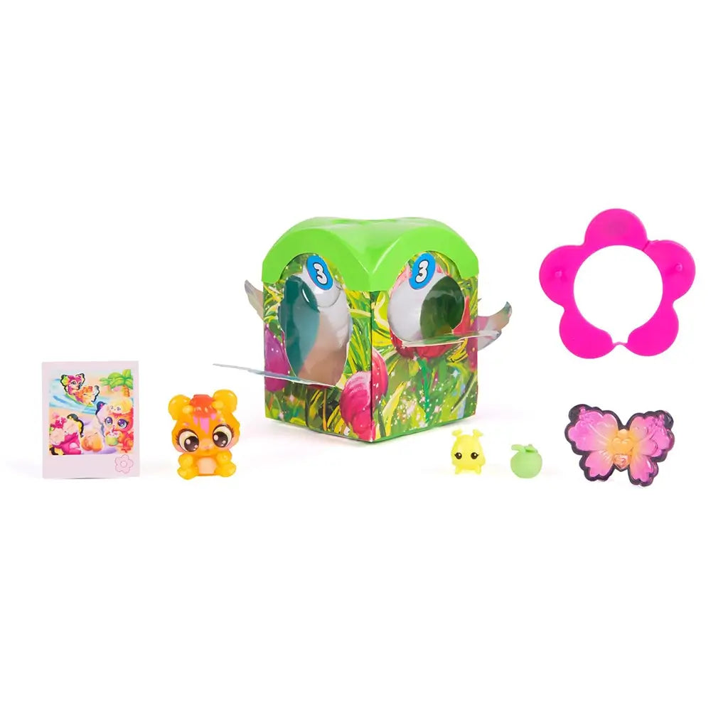 Hatchimals Bloomables surprise pack contents arranged on white background, including green blind box container, small collectible character, tiny accessories, decorative flower piece, and illustrated collector card.