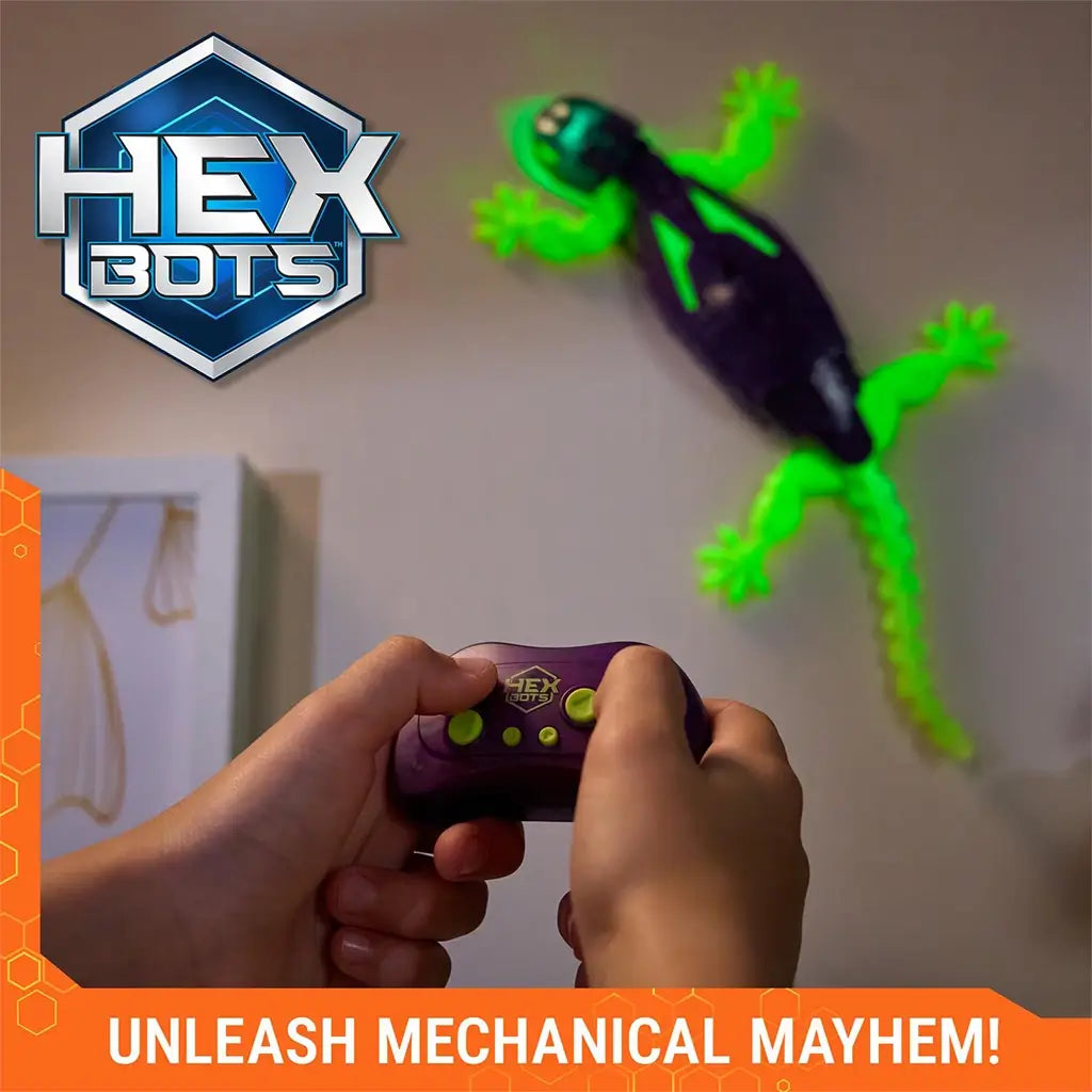 HEX BOTS Wall Crawler glow in the dark gecko in purple and neon green molded plastic with flexible tail and splayed feet, controlled by handheld remote as it climbs a smooth indoor wall.