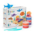 Hey Clay ocean craft kit with bright modeling clay tubs and smooth tools beside a colorful box showing rounded sea creatures on a sandy ocean scene, presented in a clean studio setting.