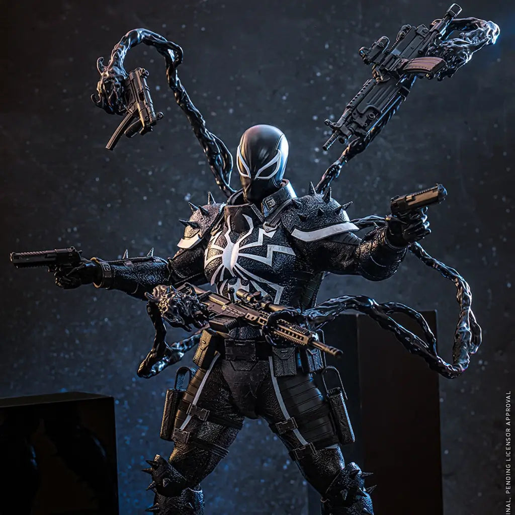 Hot Toys Agent Venom figure in black textured armor with white spider emblem, posed with pistols and rifle as symbiote tendrils hold weapons on a dark blue set.