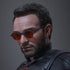 Hot Toys Marvel sixth-scale figure portrait shows a dark-haired bearded head sculpt with round red-tinted glasses and black textured costume against a plain gray backdrop.