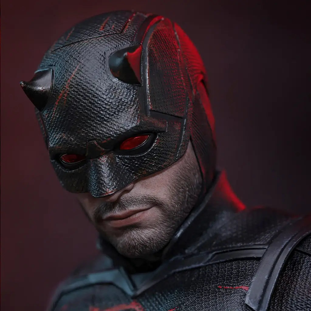 Hot Toys Marvel sixth-scale figure close-up shows a black textured horned mask with red eye lenses, exposed lower face and subtle red weathering against a dark backdrop.