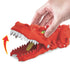 Close-up of Hot Wheels City Nemesis Dino Launcher showing a red dinosaur head with white teeth as a hand lifts its jaw, highlighting chomping action for toy cars during play.