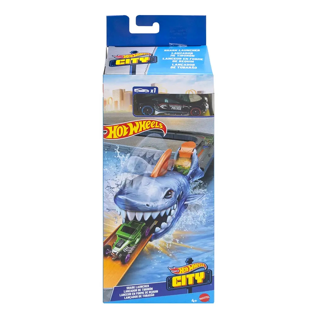 Hot Wheels City Nemesis Shark Launcher packaging showing a large illustrated shark with a wide mouth, launching a green car on track, with included black police-style toy car visible in window.