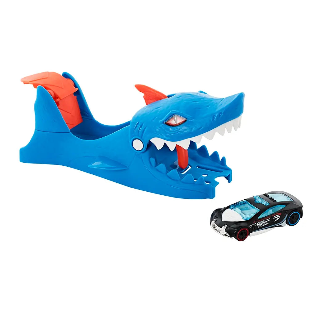 Hot Wheels City Nemesis Shark Launcher toy with blue shark-shaped design, orange fins, wide white teeth, and included black police-themed die-cast car with blue accents.