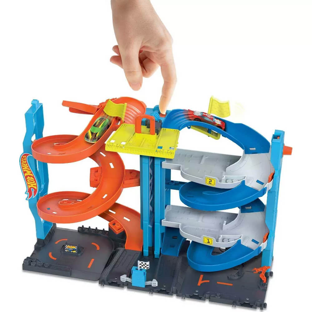 Hand pushing button putting the cars in motion on the Hot Wheels City Transforming Race Tower Playset