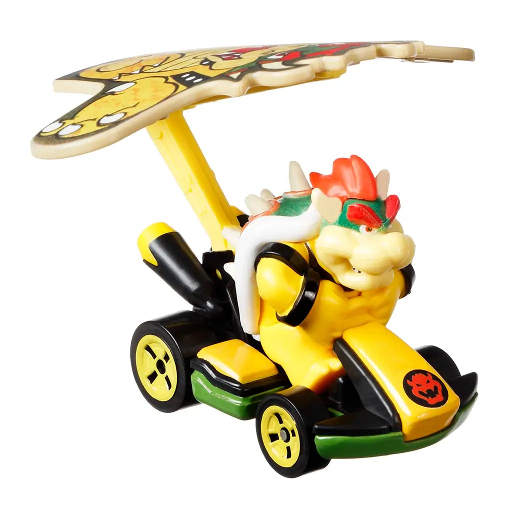 Hot Wheels Mario Kart Bowser diecast car in yellow and black with green details, featuring Bowser figure, large kite-shaped glider, and detailed wheels on white background.