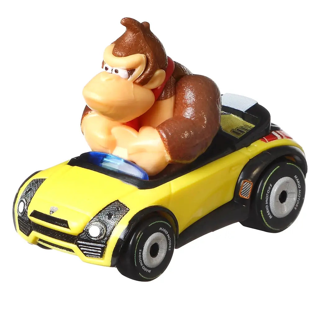Angled close-up of Hot Wheels Donkey Kong Sports Coupe diecast car highlighting yellow body, black bumper details, silver wheels, and sculpted Donkey Kong character.