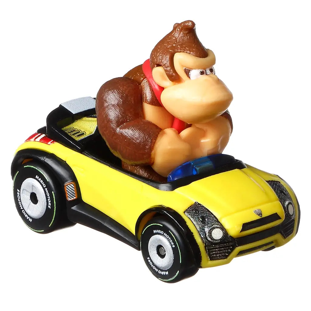 Diecast Hot Wheels Donkey Kong Sports Coupe car toy featuring a yellow body, black trim, detailed tires labeled Mario Motors, and molded Donkey Kong figure gripping the wheel.