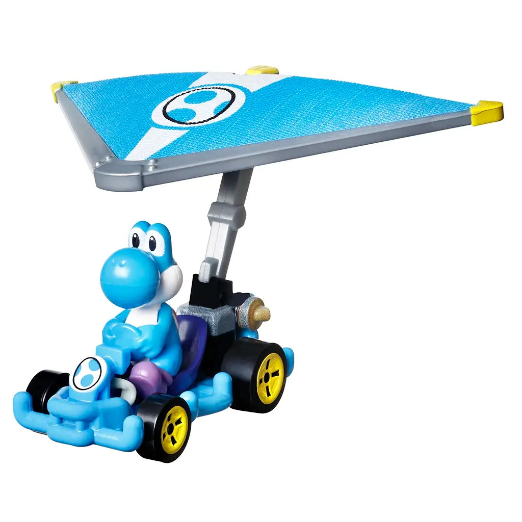 Collectible Hot Wheels Mario Kart Light-Blue Yoshi toy car shows a plastic Yoshi figure in a bright blue kart with yellow wheels and a large silver and blue glider attachment for flying action play.