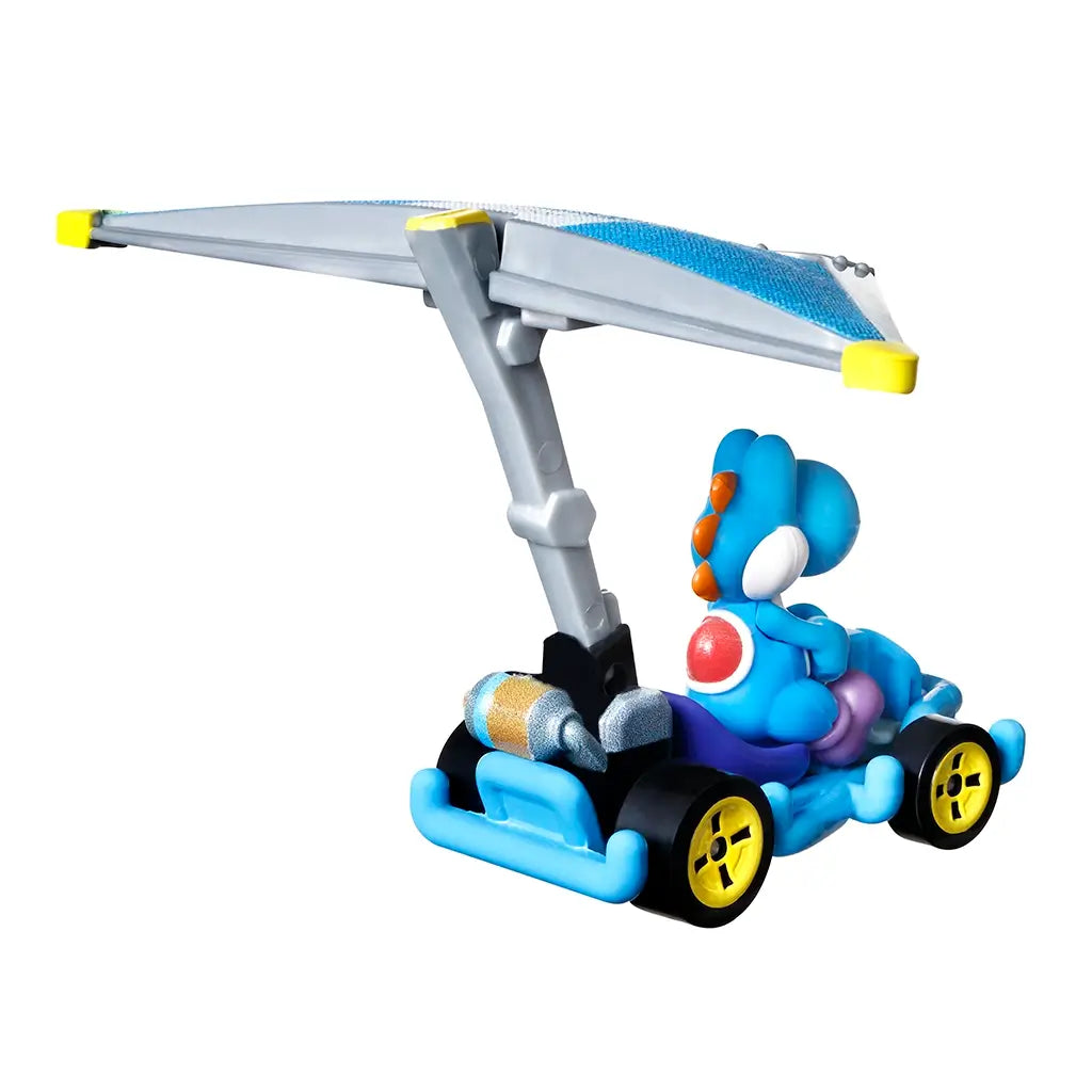 Hot Wheels Mario Kart Light-Blue Yoshi diecast car features a glossy blue figure in a kart with bright yellow wheels, metallic engine details, and a silver-gray super glider wing for racing play.