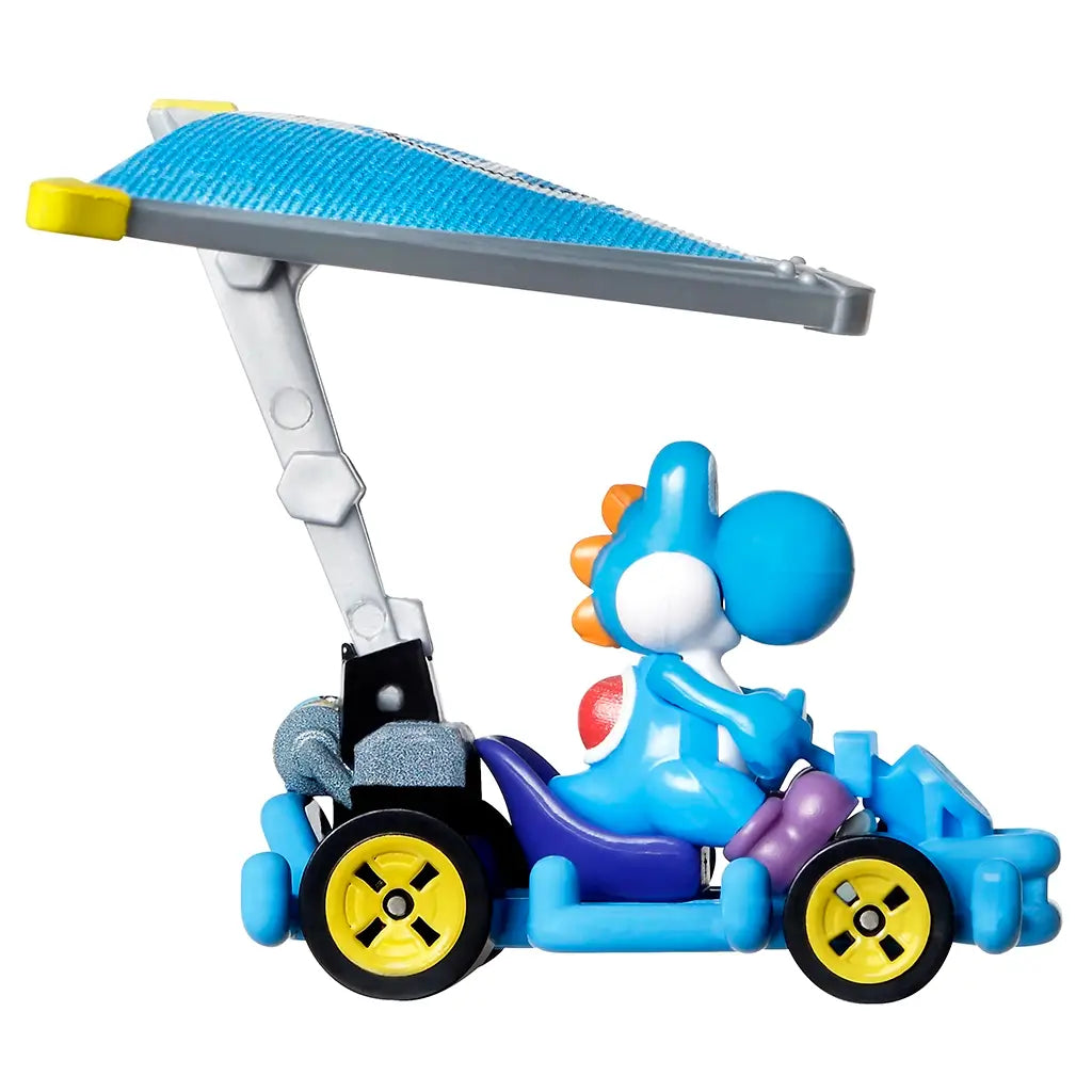 Side profile of Hot Wheels Mario Kart Light-Blue Yoshi diecast car highlights the detailed kart frame, large rear-mounted glider wing, bright yellow wheels, and seated Yoshi character in vibrant blue.