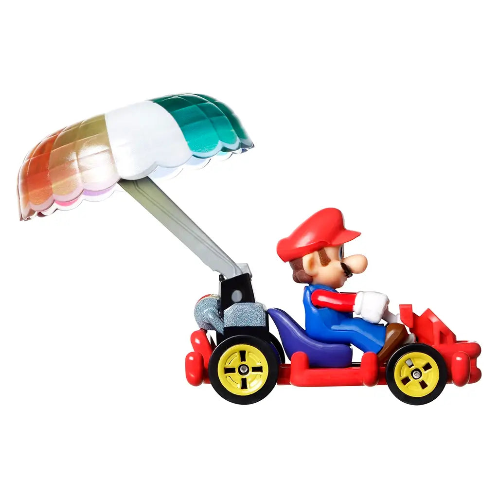 Hot Wheels Mario Kart diecast car featuring Mario in a red and blue pipe frame kart with bright yellow wheels and a raised rainbow parachute glider attachment.