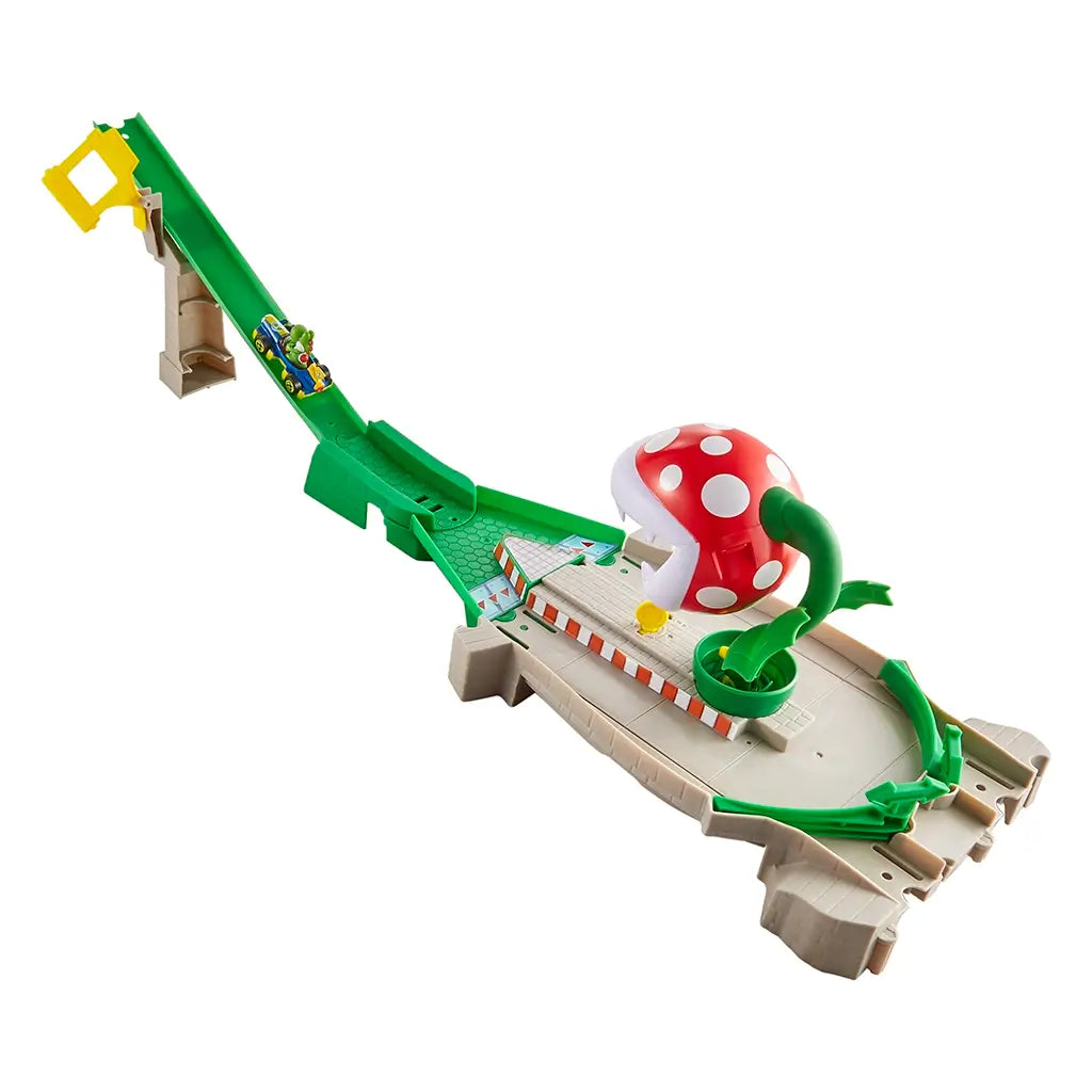 Angled view of Hot Wheels Mario Kart Piranha Plant track playset with raised green slide ramp, chomping red plant, and small yellow coin detail on the tiled finish platform.