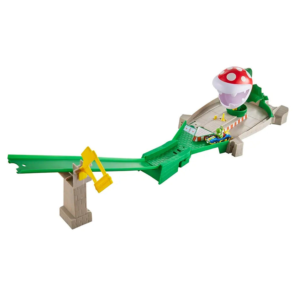Hot Wheels Mario Kart Piranha Plant track set with green ramp, yellow launcher, and a red chomping Piranha Plant obstacle, including a small Yoshi kart figure at the end.