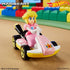 Hot Wheels Mario Kart Princess Peach kart in pink and yellow plastic racing across a toy track scene, showing the seated character figure, rolling gold wheels, and standard kart shape within a colorful playset setting.