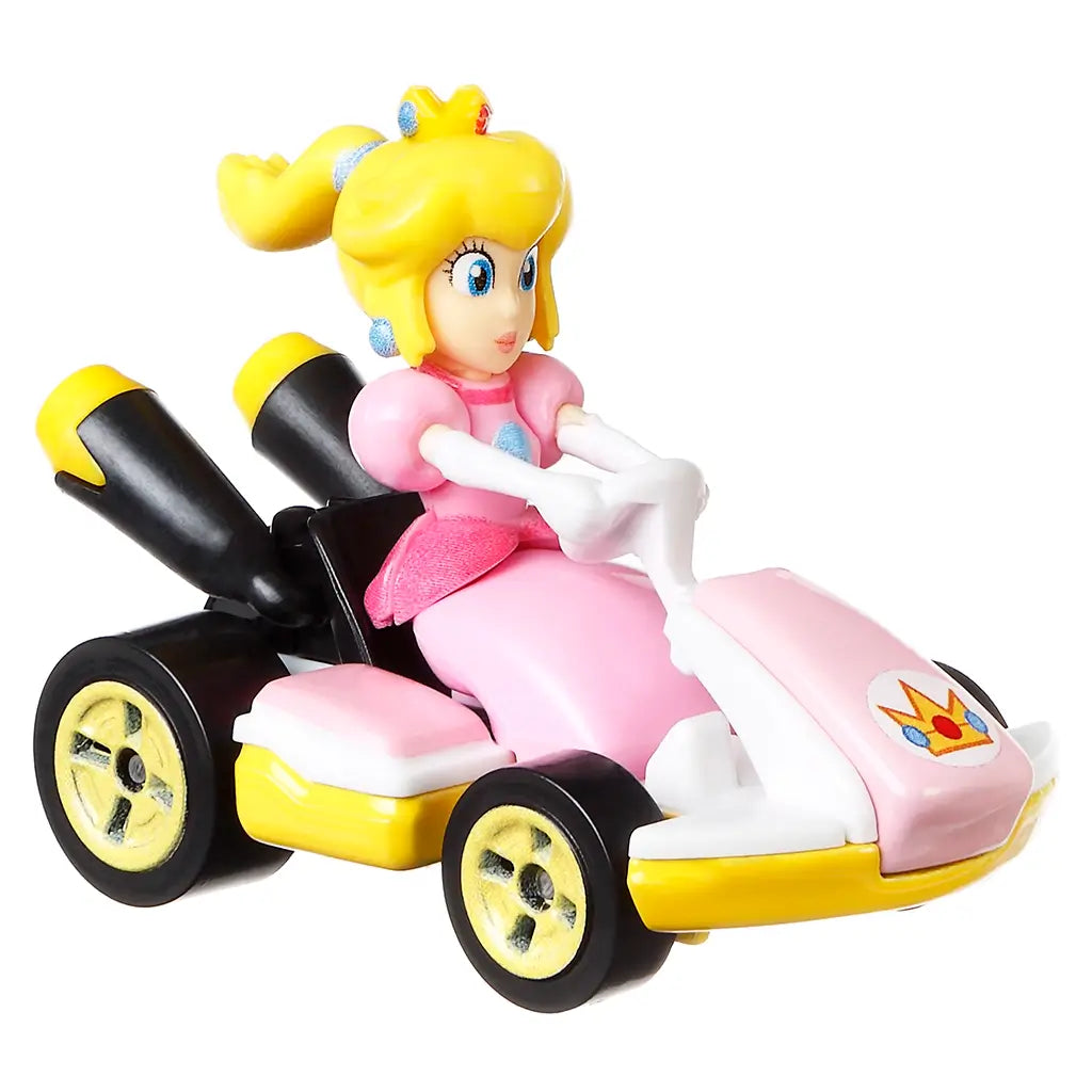 Hot Wheels Mario Kart Princess Peach kart toy in pink and yellow glossy plastic with a compact racing form, featuring Princess Peach seated at the wheel, gold-accent wheels, and twin exhausts on a clean white background.