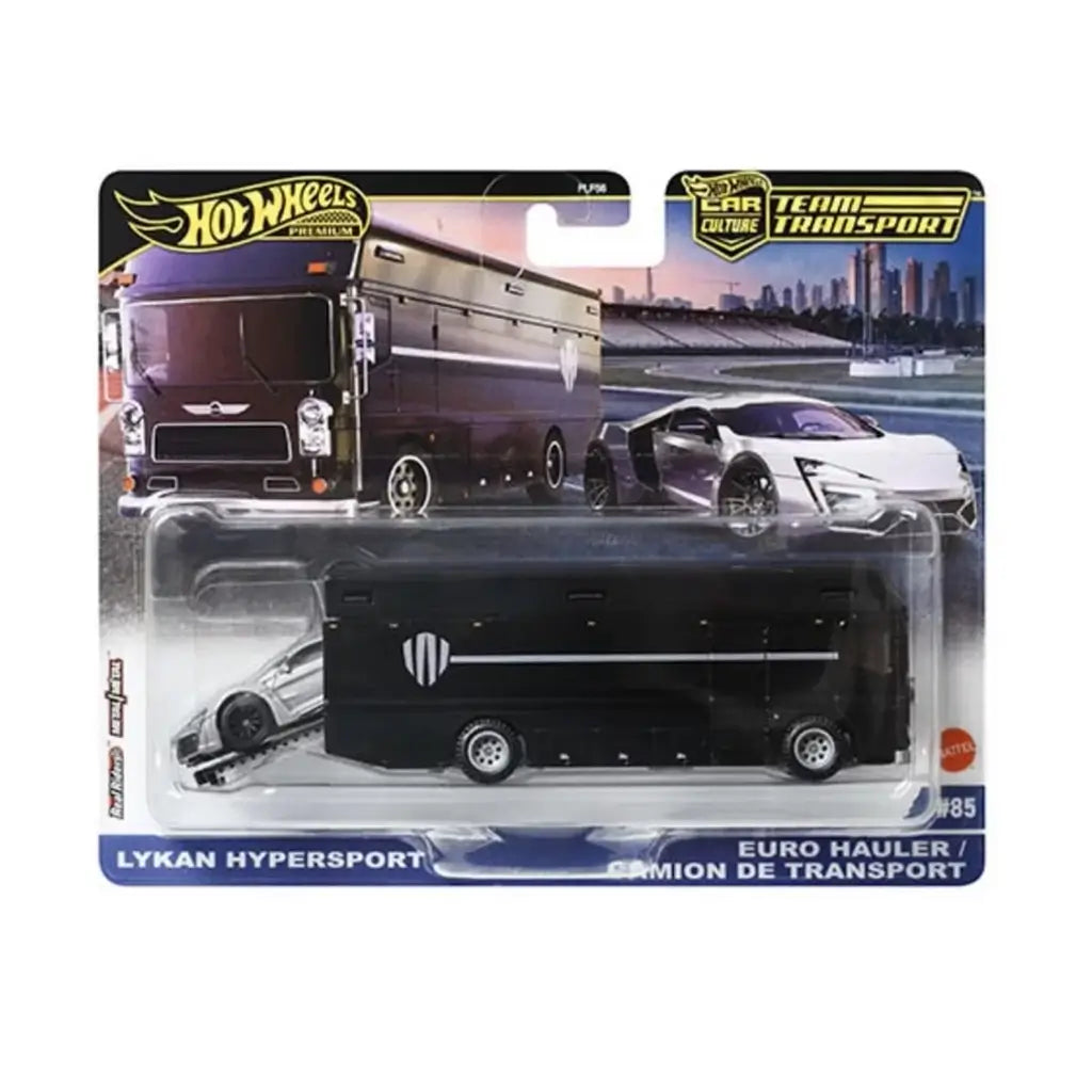 Hot Wheels Team Transport set shows a glossy black Euro Hauler with silver stripe graphics and a Lykan Hypersport image on the card, packaged against a racetrack skyline backdrop for premium collector display appeal.
