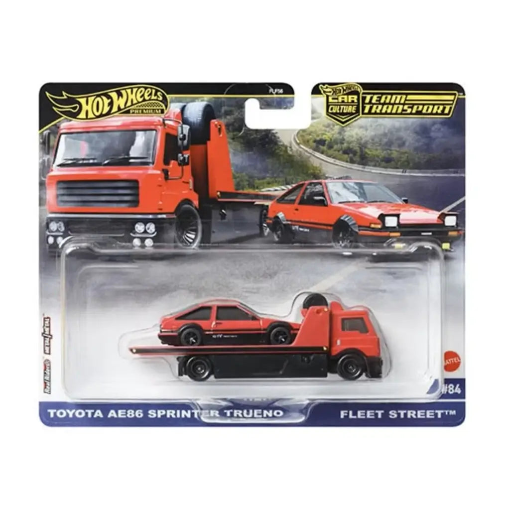 Hot Wheels Toyota AE86 packaging displays the red metal flatbed truck and AE86 coupe in a molded plastic blister, with bold car-culture artwork and a scenic road backdrop highlighting the transport theme.