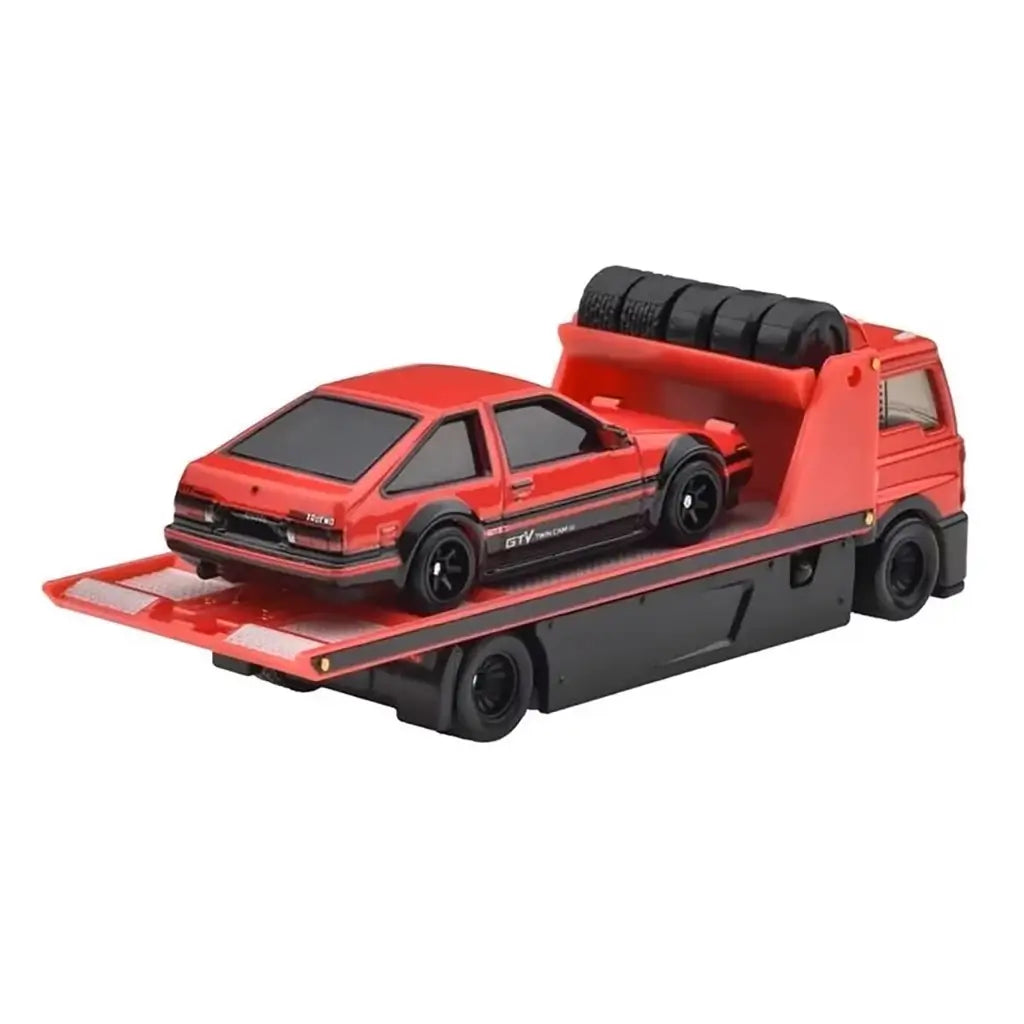 Hot Wheels Toyota AE86 set depicts the red metal flatbed truck with reflective deck texture carrying the sleek AE86 coupe, shown in a close rear angle against a simple white background.