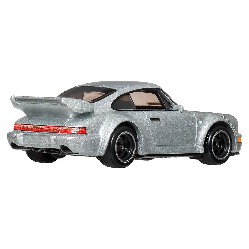 Hot Wheels Porsche 911 Carrera RS 3.8 diecast car in metallic silver metal with wide rear fenders, red tail light strip, black wheels, dual exhaust detail, and raised rear wing, shown from a rear angled view on white.