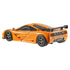 Rear angled view of Hot Wheels McLaren F1 GTR 1995 die-cast model in orange, showing dual exhausts, detailed taillights, large black rear wing, and sculpted side panels against white background.