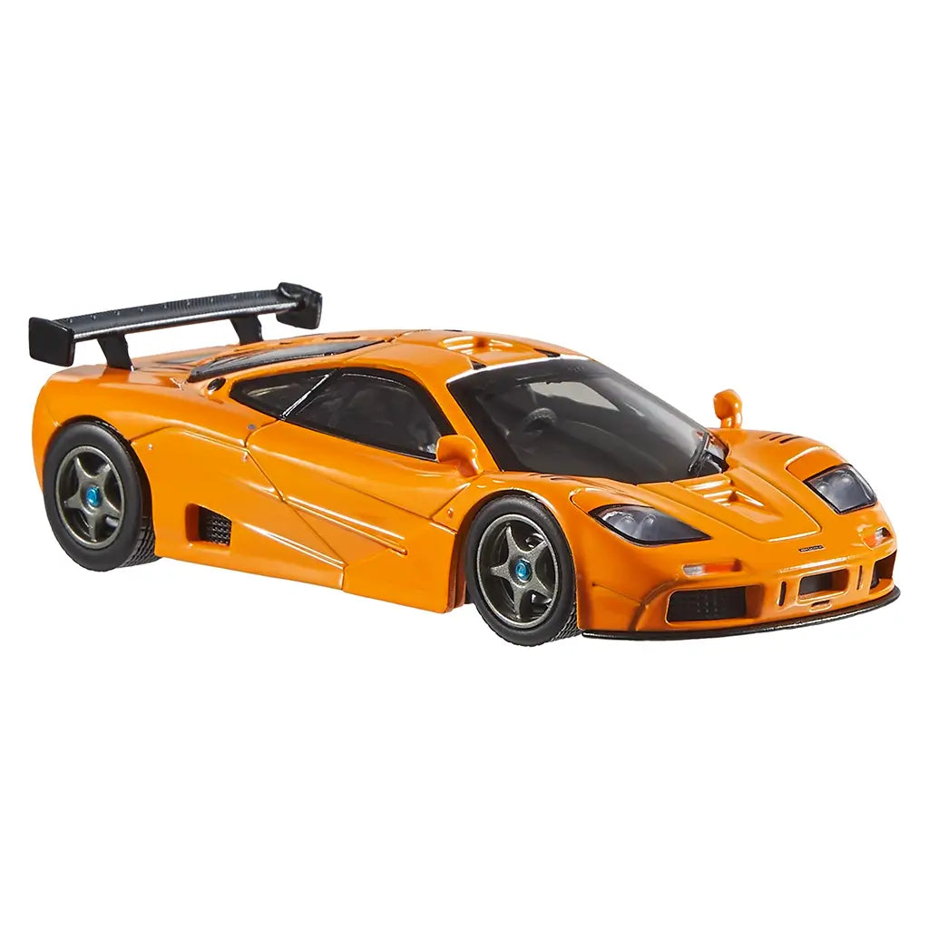 Front angled view of Hot Wheels 1995 McLaren F1 GTR die-cast toy car in bright orange, emphasizing low stance, black spoiler, sculpted vents, racing wheels, and tinted glass on white background.