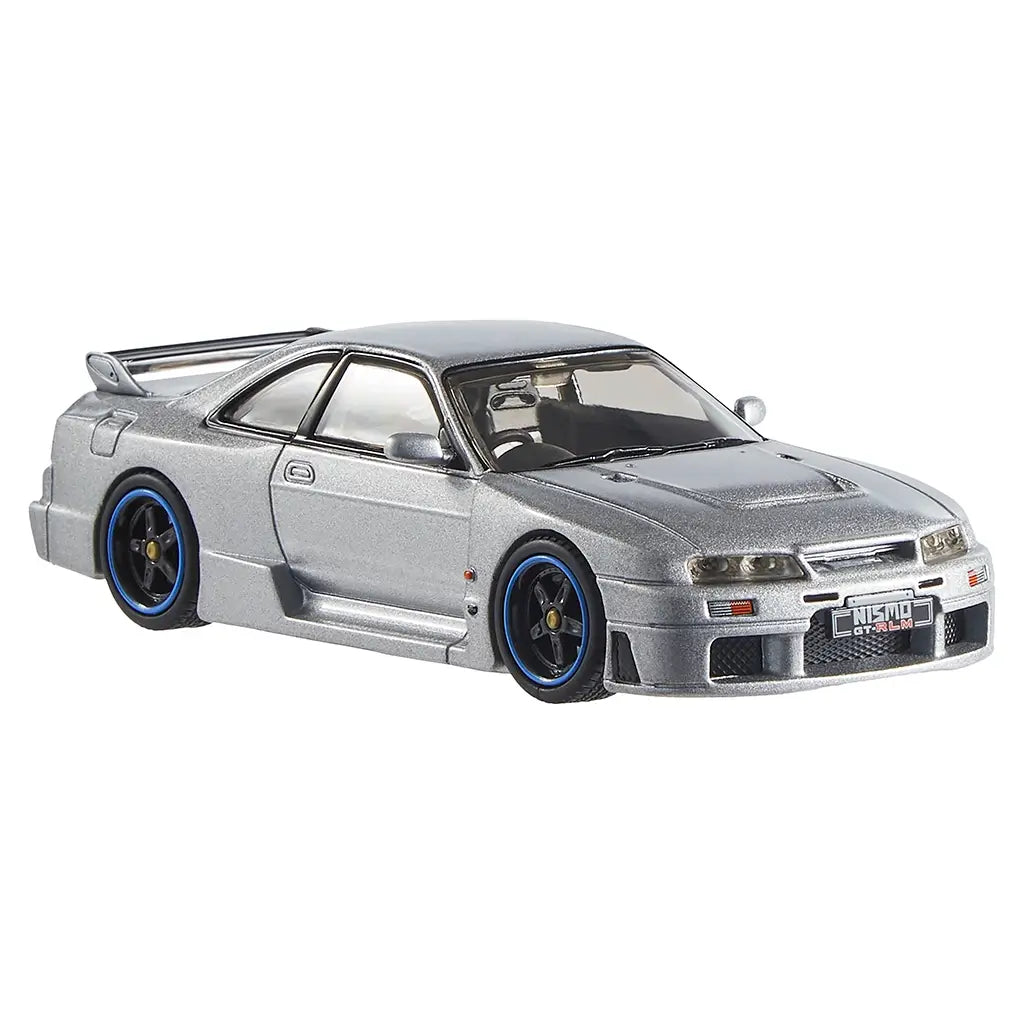 Hot Wheels Nismo GT-R LM diecast car in metallic silver finish with low stance, hood vents, flared side skirts, black wheels with blue accents, and detailed grille.