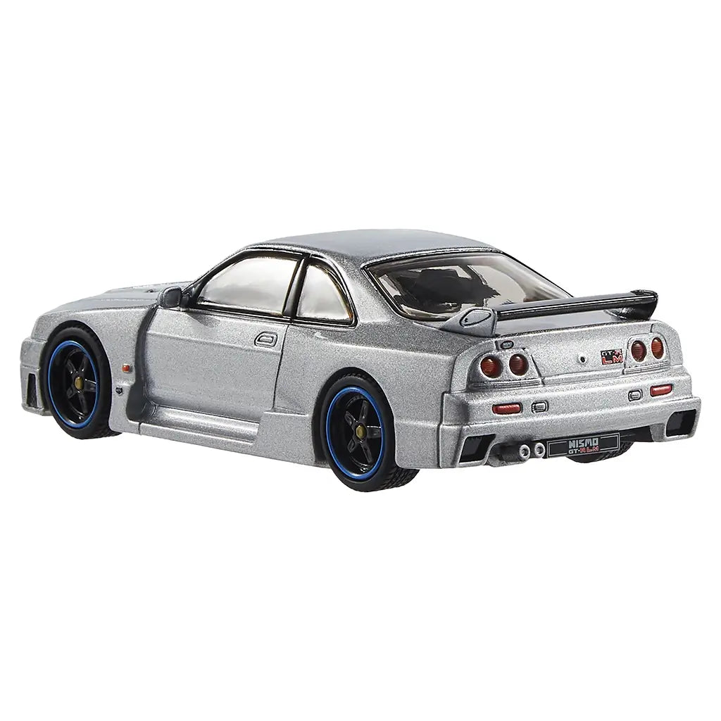 Metallic silver Nismo GT-R LM Hot Wheels diecast viewed from rear angle, showing wide bumper, quad taillights, dual exhaust pipes, and oversized racing spoiler detail.