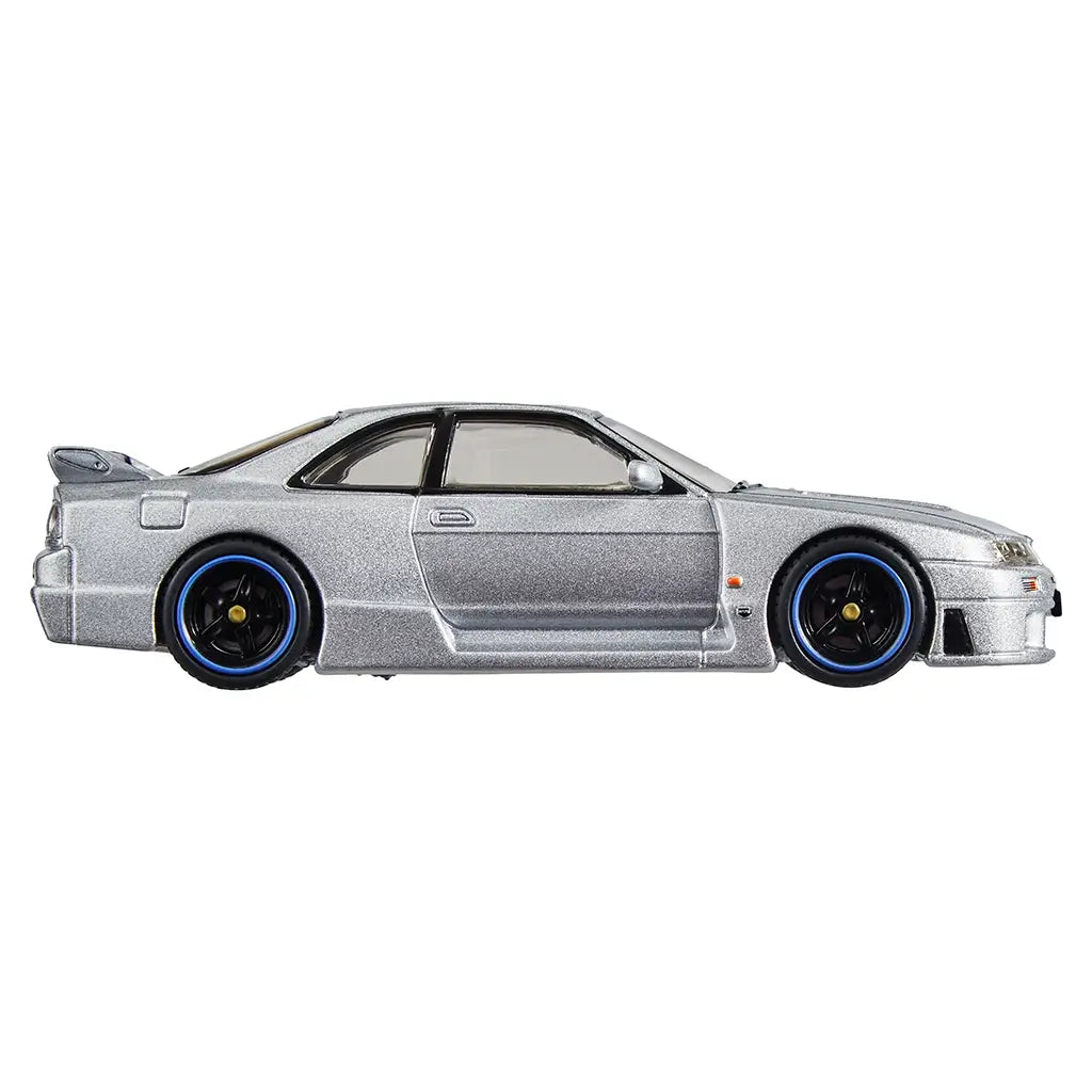 Side profile of Hot Wheels Premium Nismo GT-R LM in metallic silver, showcasing aerodynamic coupe shape, extended side skirts, tinted windows, and black wheels with blue trim.