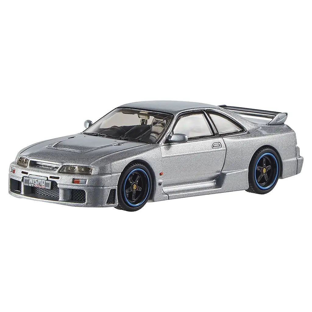Silver Hot Wheels Nismo GT-R LM diecast car with metallic finish, black racing wheels with blue trim, wide body kit, and aerodynamic rear spoiler on a 1:43 scale model.